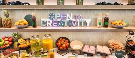 Buffet com diversos alimentos e um letreiro que diz 'OPEN CREATIVITY'.