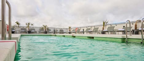 Una piscina al aire libre de temporada, sillones reclinables de piscina