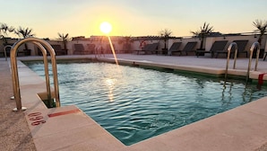 A swimming pool with sunlit water, lounge chairs, and a lifebuoy. - ibis Styles Madrid Airport Valdebebas (Madrid)