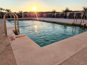 A swimming pool with sunlit water, lounge chairs, and a lifebuoy. - ibis Styles Madrid Airport Valdebebas (Madrid)