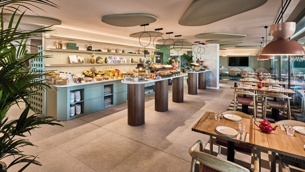 Ein modernes Restaurant mit einem zentralen Buffet, hohen Decken und zeitgenössischer Beleuchtung.