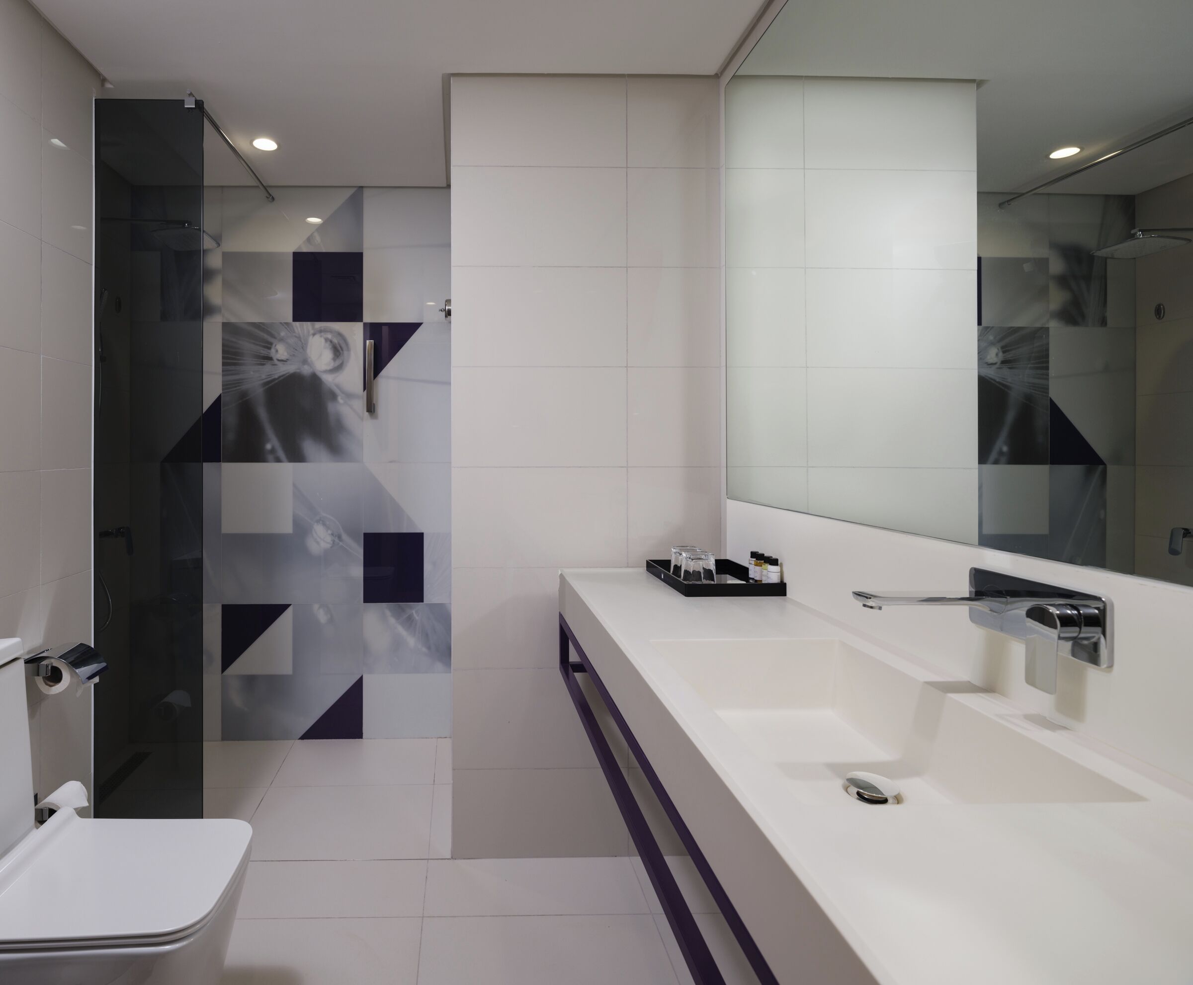 A modern bathroom with a glass shower enclosure, a white sink with a mirror, and a toilet.