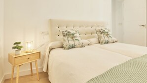 A bedroom with a bed, a bedside table with a lamp, and a small plant.