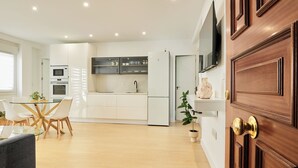 A modern kitchen with white cabinetry, a built-in oven, and a refrigerator.