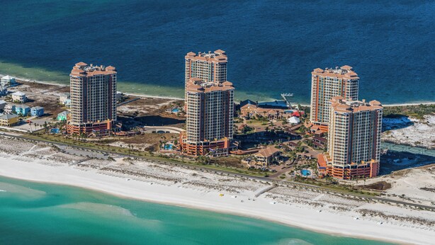 Un complexe hôtelier situé sur la côte, composé de plusieurs immeubles de grande hauteur, doté d’une plage et offrant une vue dégagée sur l’océan.