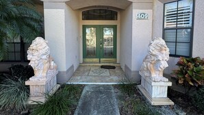 L’entrée d’un immeuble, avec une porte verte, le numéro 409, et deux statues de lions de chaque côté.