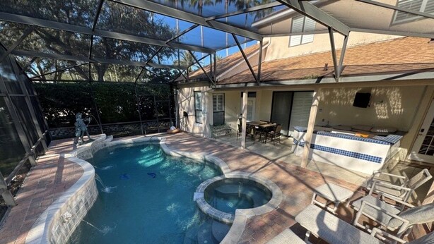Une piscine avec un jacuzzi, entourée de chaises longues et dotée d’un patio couvert.