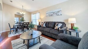 Ein Wohnzimmer mit einer Couch, zwei Beistelltischen, einem Couchtisch und einem Essbereich mit Stühlen und einem Tisch.