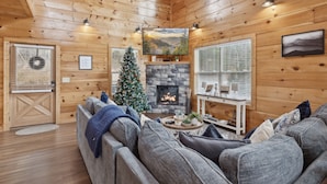 Een gezellig cabin interieur met een open haard, een kerstboom en een comfortabele zithoek.