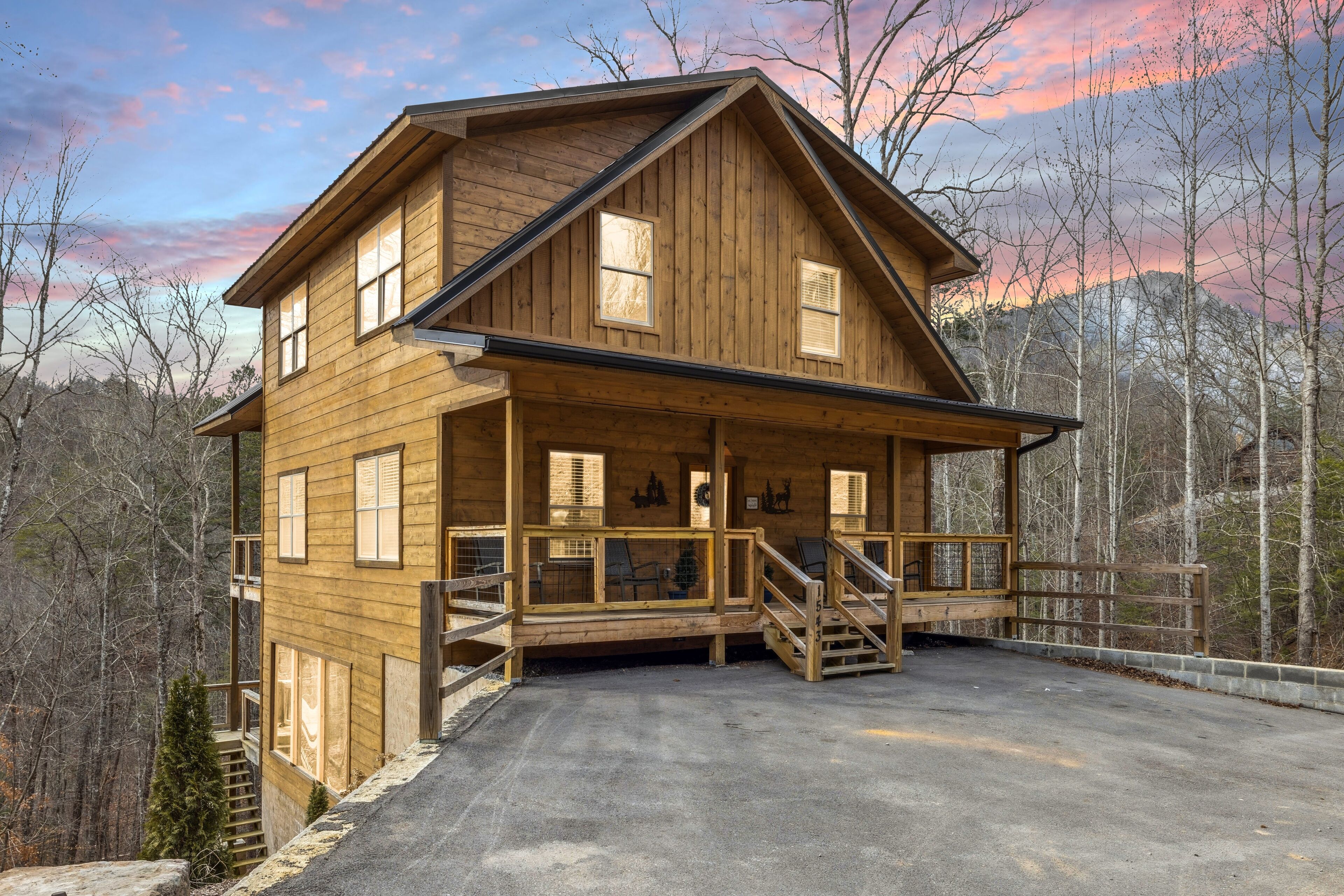 A wooden cabin with a porch and a staircase leading to a deck.