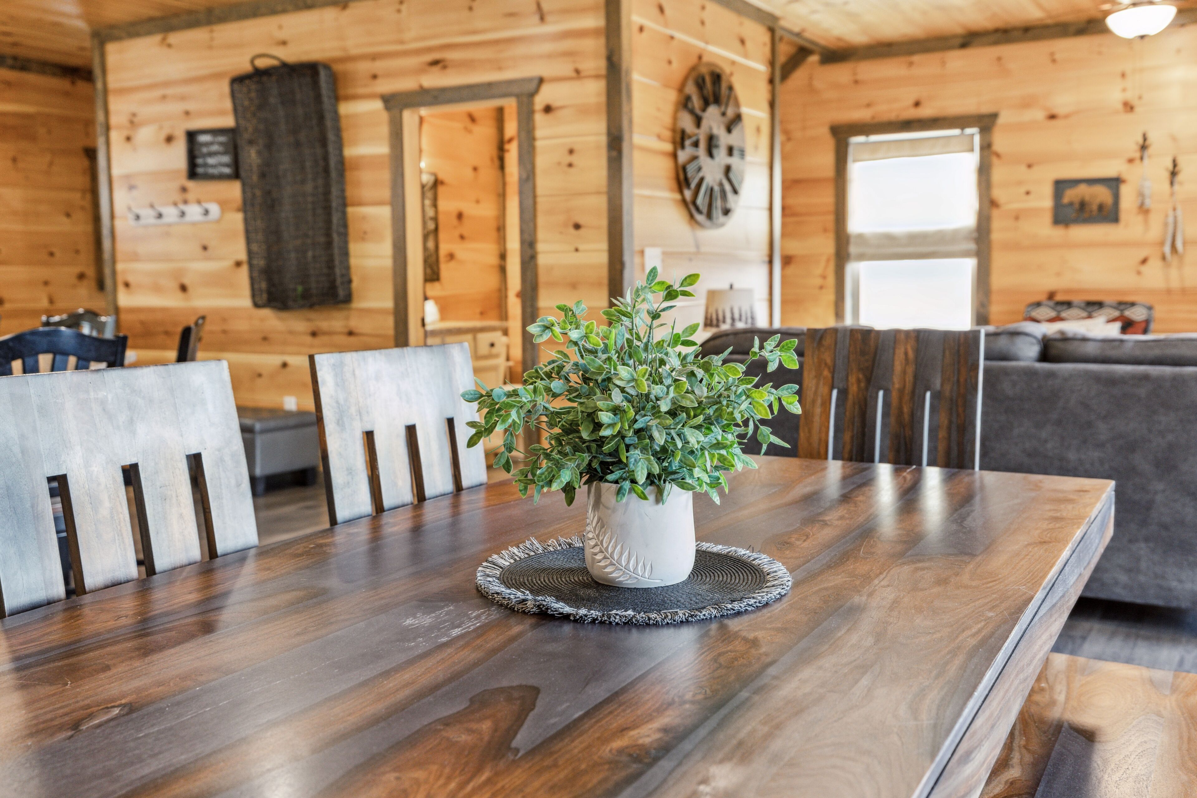 Un interior de madera con una mesa de comedor, sillas, una planta en maceta y un sofá.