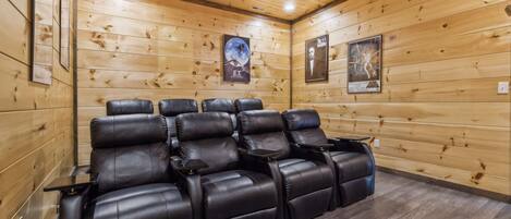 A wooden-paneled room with reclining leather chairs and a poster on the wall.