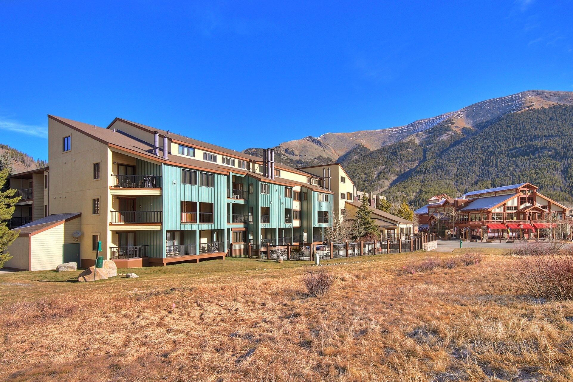Et hotel med flere etager, altaner, et skihus og et bjergrigt landskab i baggrunden.