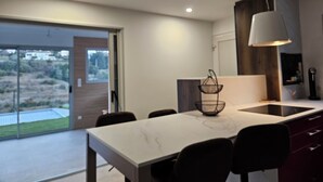 A modern kitchen with a large island, dark cabinetry, and a view through the glass door. - New villa with pool and spa, Aubenas (Aubenas)