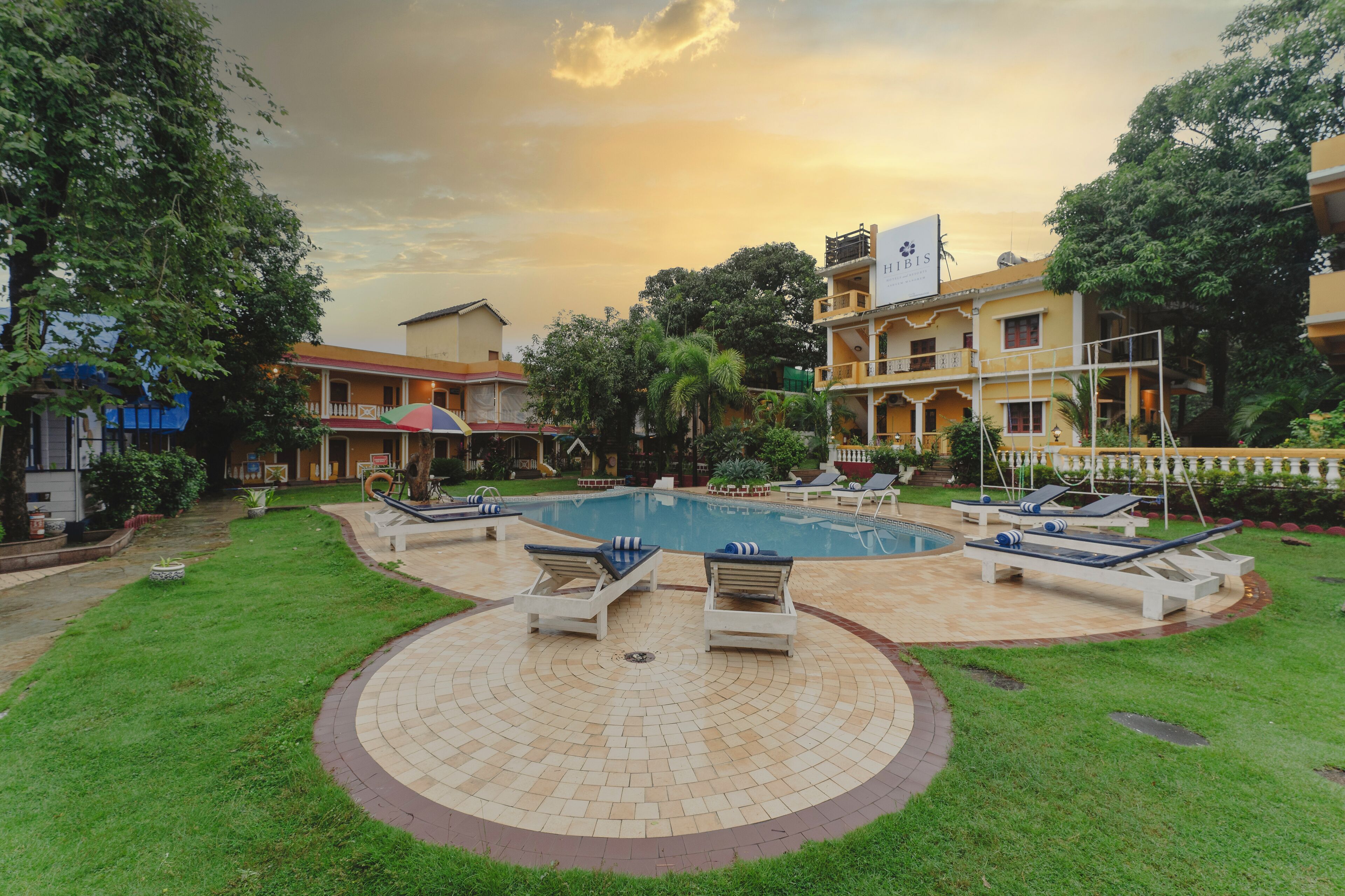 A pool area with lounge chairs, a circular tiled deck, and surrounding greenery.