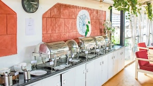 Montaje de bufé con varias estaciones de comida, un reloj y una pared decorativa con diseño floral.