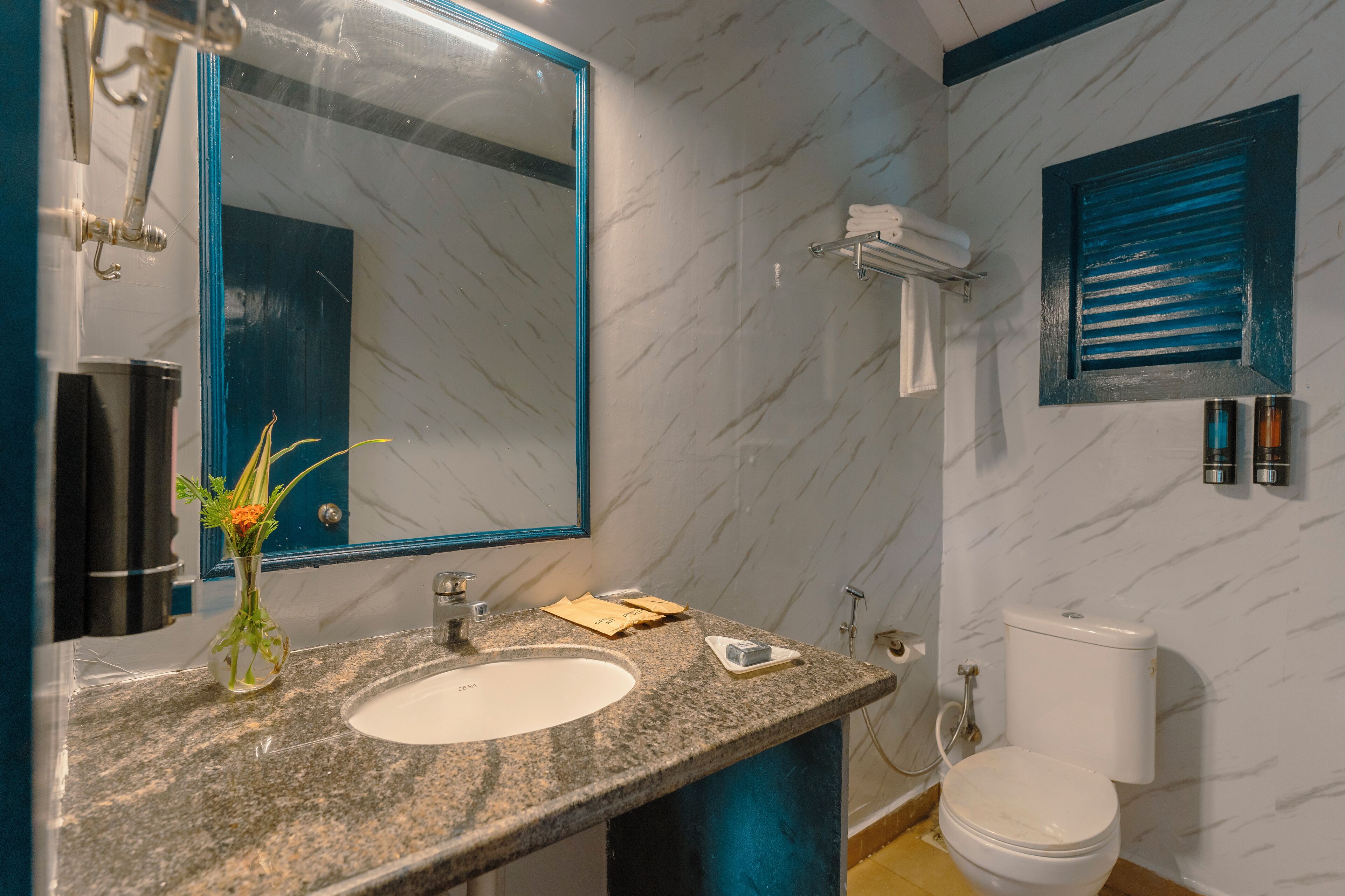 Ein Badezimmer mit Marmorwaschbecken, Spiegel, Toilette und Handtuchhalter.