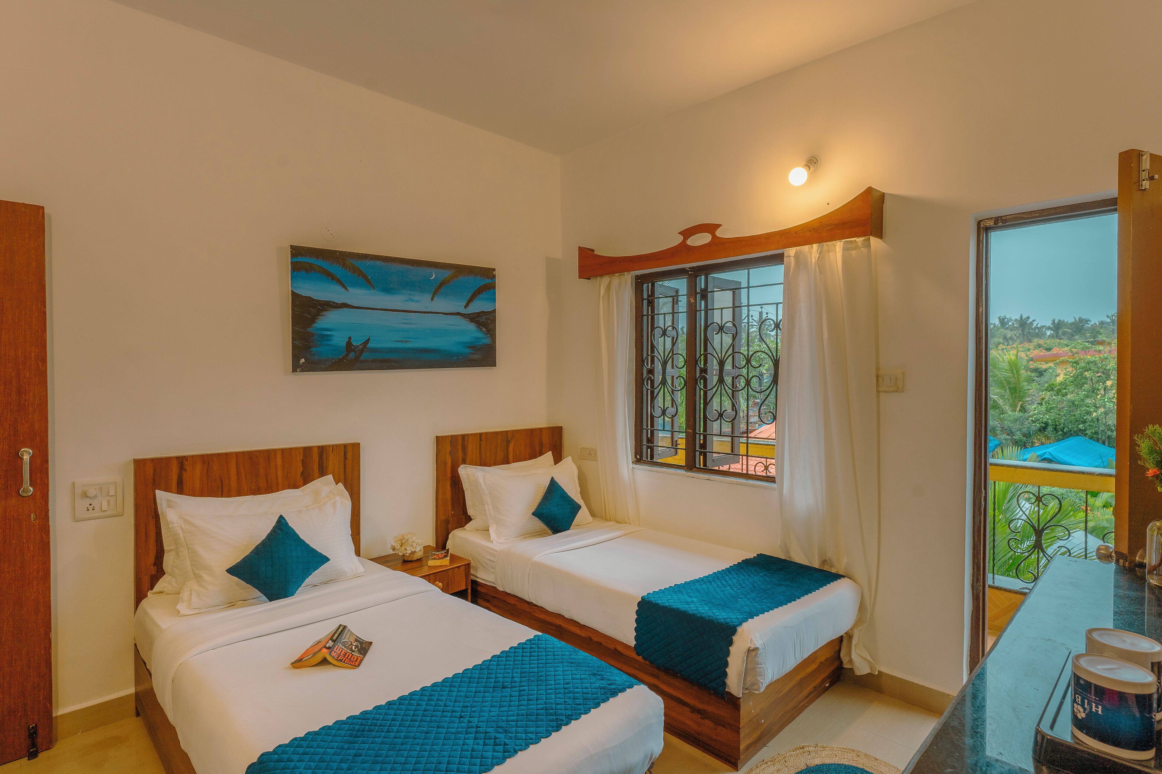 Habitación de hotel con dos camas, un cuadro, una ventana con cortinas y un balcón con vistas.