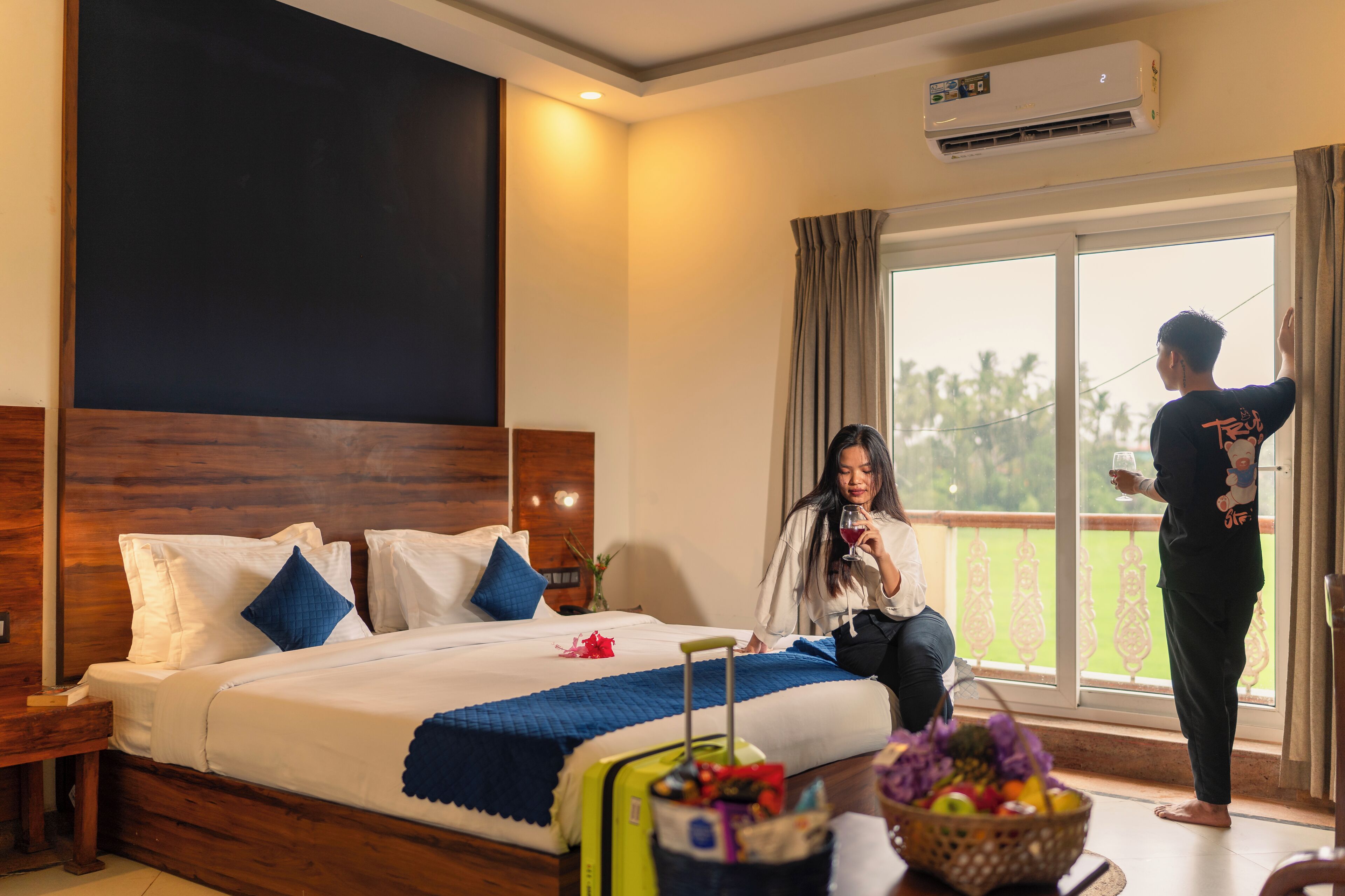 A hotel room with a large bed, a balcony, and a view of palm trees.