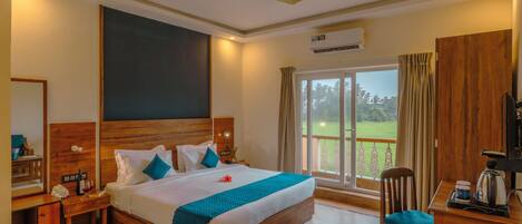 Habitación de hotel con una cama grande, un escritorio con silla, ventilador de techo y vistas al exterior.