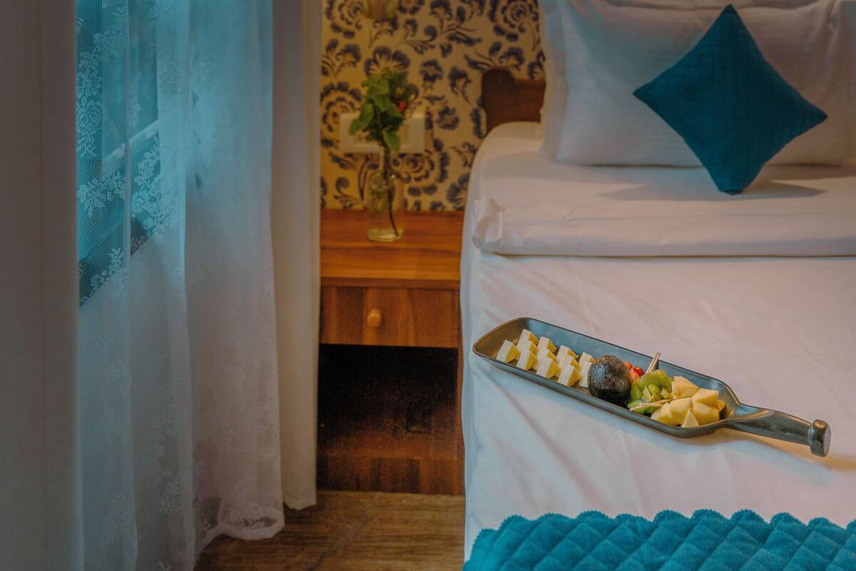 Ein Schlafzimmer mit einem Bett, einem Nachttisch mit einer Vase und einer Auswahl an Snacks auf dem Bett.