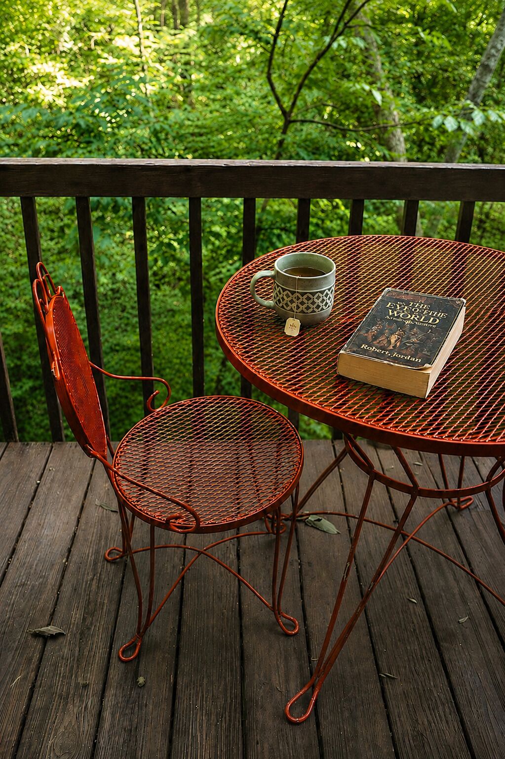 Un tavolo in metallo con un libro e una tazza su un pontile in legno, con una sedia in metallo.