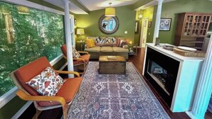 A living room with a sofa, chairs, a coffee table, a fireplace, and a large window with a view.