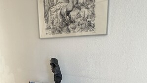 A room with a black glass table, a wooden bench, a framed artwork of a horse, and a small owl statue. - 5th floor, charming 2-bedroom apartment , Centre of Geneva (Genève)