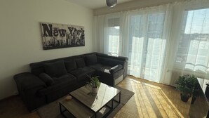 A living room with a dark-colored sofa, a coffee table with a plant, and a cityscape artwork on the wall. - 5th floor, charming 2-bedroom apartment , Centre of Geneva (Genève)