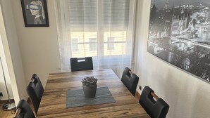 A dining area with a large wooden table, black chairs, a potted plant, and a cityscape painting on the wall. - 5th floor, charming 2-bedroom apartment , Centre of Geneva (Genève)