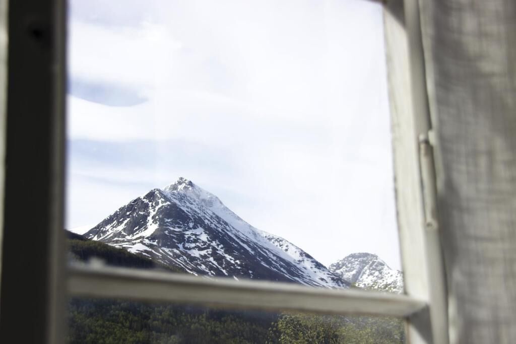A mountain view through a window with a wooden frame.
