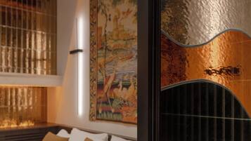 A bed with white bedding and two brown pillows, a wooden ceiling, a wall with a textured artwork, and a black headboard.