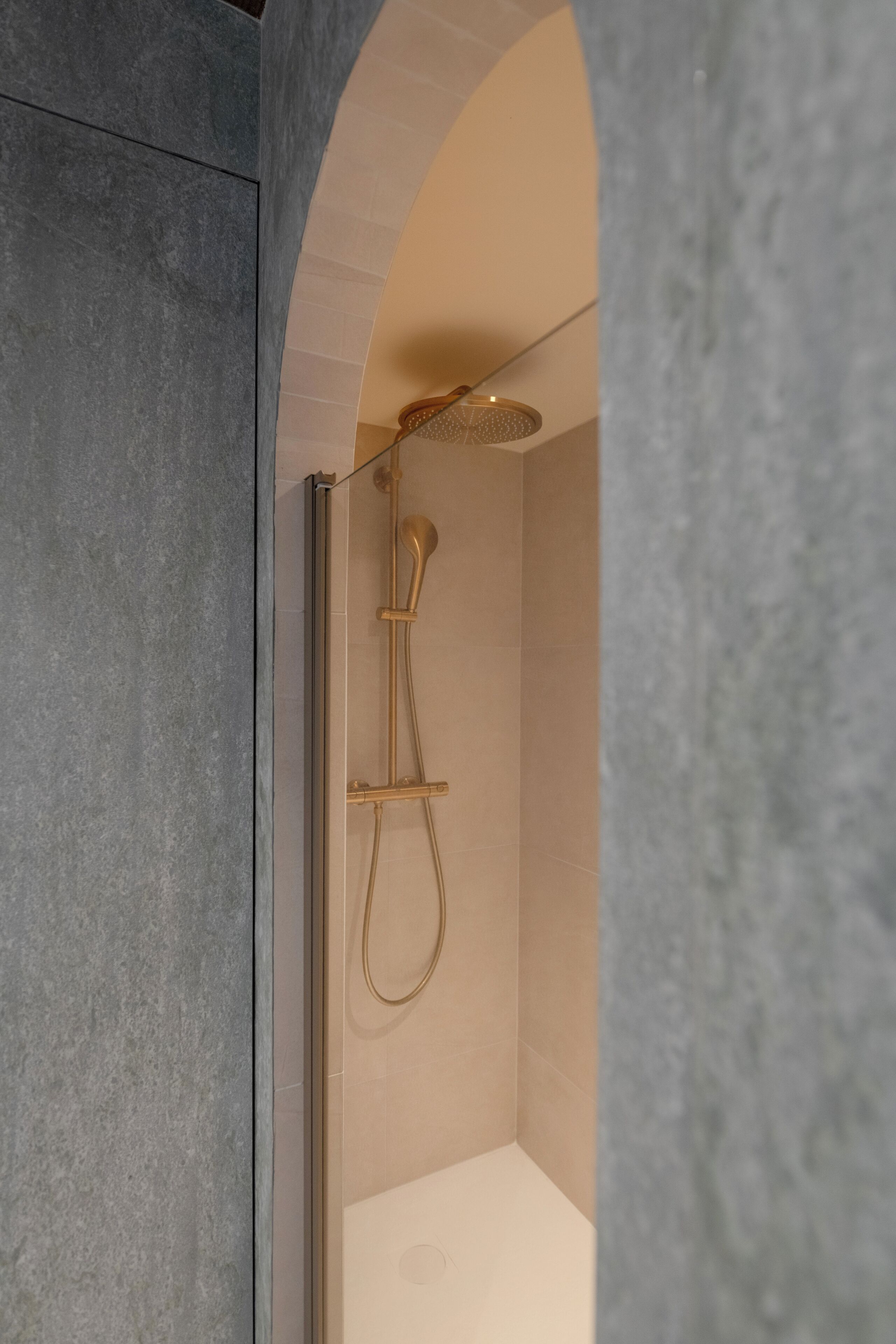 A modern shower enclosure with a glass door, a handheld showerhead, and a wall-mounted control panel.