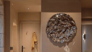 Une pièce moderne avec un miroir rond, une table ronde entourée de chaises et une porte sur laquelle est accrochée une serviette.