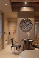 Una habitación moderna con un espejo redondo, una mesa redonda con sillas y una puerta con una toalla colgada.