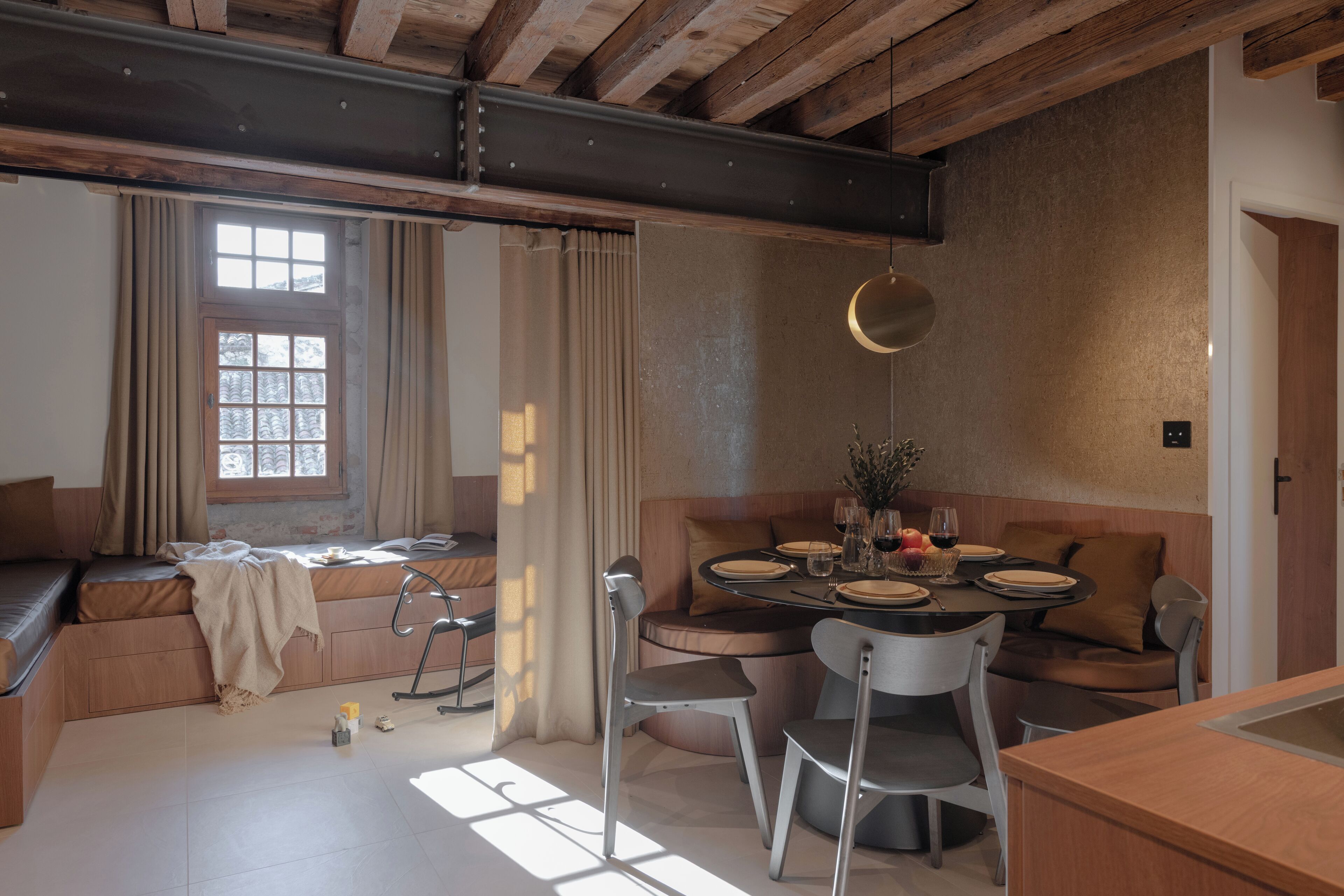 A cozy dining area with a wooden table set for four, surrounded by cushioned seating.