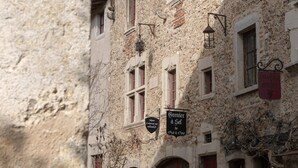 Un bâtiment en pierre doté de nombreuses fenêtres, d’une porte rouge et d’une enseigne indiquant qu’il s’agit d’un commerce.