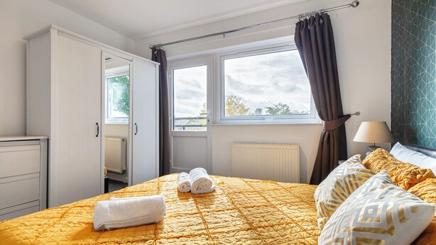 A hotel room with a bed, a window, a radiator, and a wardrobe.