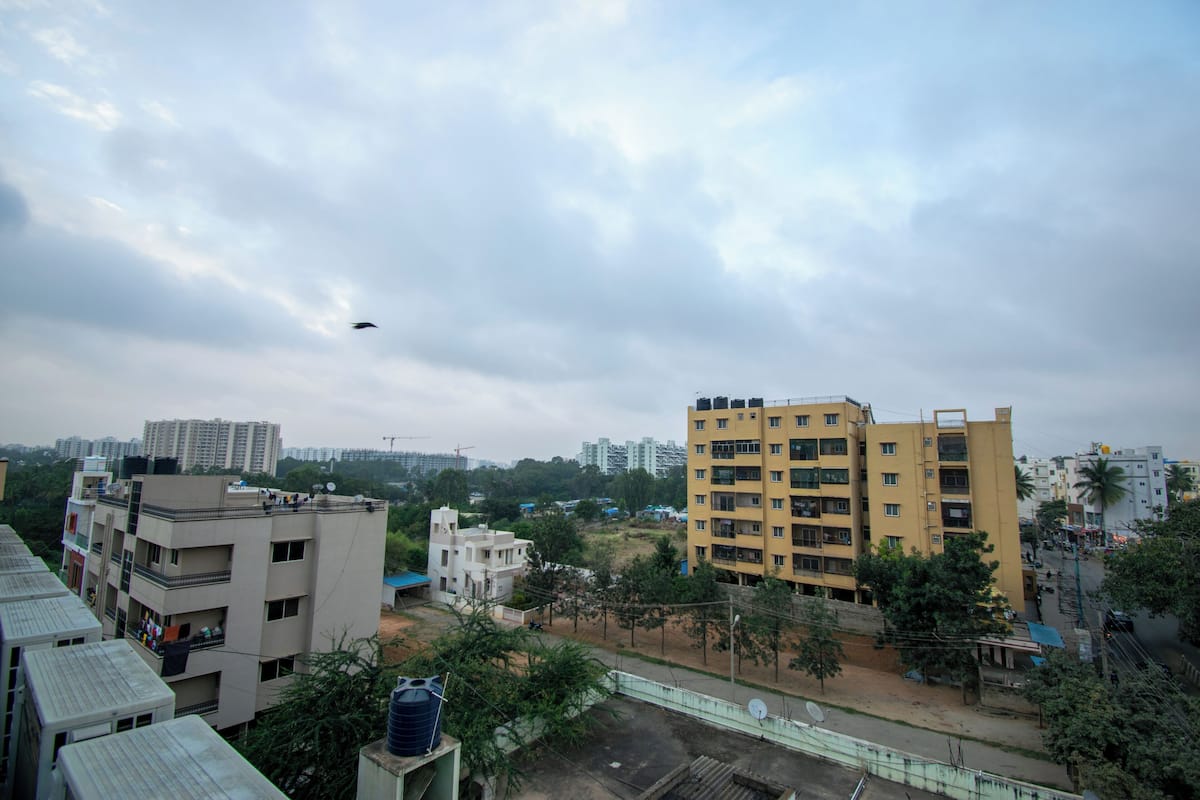 A residential area with multi-story buildings, some with balconies, and a few trees.