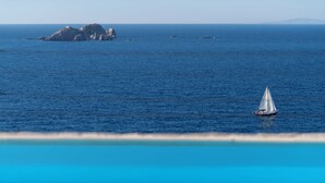 Un voilier sur une mer calme, avec une île rocheuse en arrière-plan.
