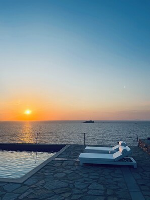 Ein Sonnenuntergangsblick von einem Poolbereich mit Liegestühlen und einer Stegterrasse.