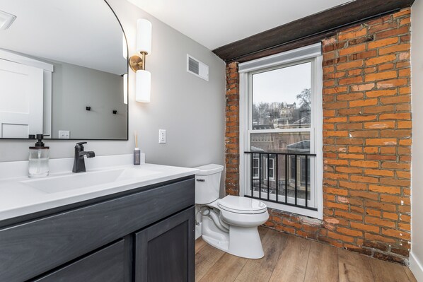 Un baño moderno con un espejo grande, lavamanos blanco y muebles oscuros.