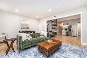 Una sala de estar moderna con un sofá verde, una mesa de centro de madera y una alfombra azul estampada.