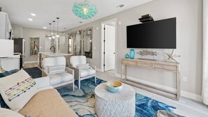 A modern living room with a large TV, comfortable seating, and a decorative console table.