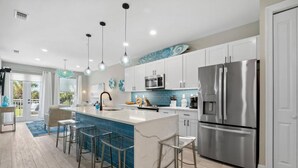A modern kitchen with white cabinets, stainless steel appliances, and a blue-tiled backsplash.