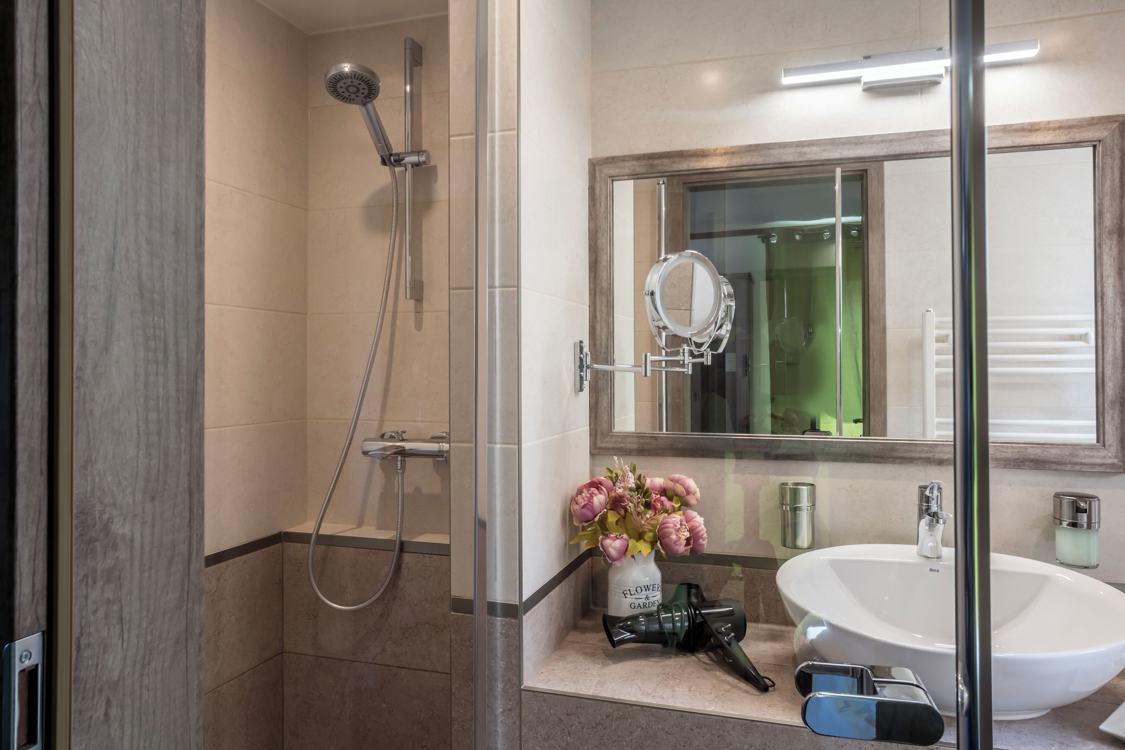 Un baño moderno con ducha de vidrio, un lavabo grande y un espejo encima.