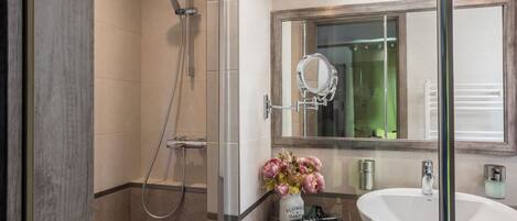 Un baño moderno con ducha de vidrio, un lavabo grande y un espejo encima.