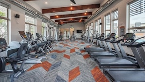 Une salle de sport équipée de tapis de course, de vélos elliptiques et d’appareils de musculation disposés en rangées.