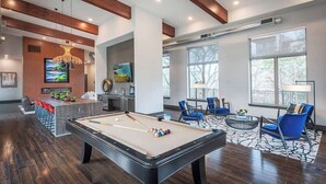Un espace de détente moderne doté d’une table de billard, de sièges confortables et de grandes fenêtres offrant une vue panoramique.