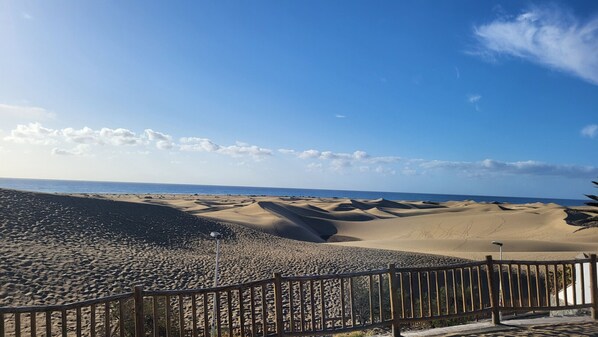 A sandy beach with dunes and a clear sky.